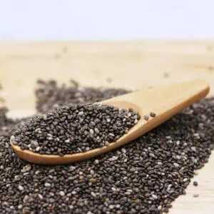 Bulk Chia Seeds in wooden spoon and on wooden board